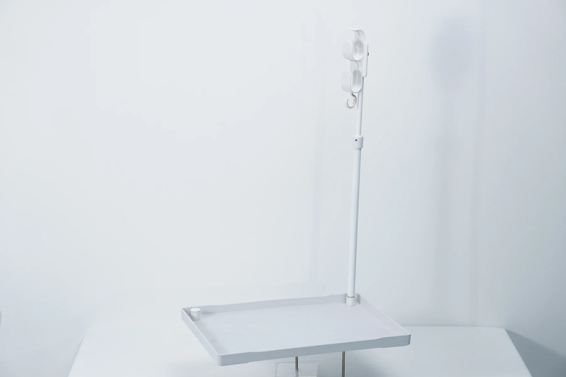Finished white CPAP hose holder with a tray, upright support and hose hooks.